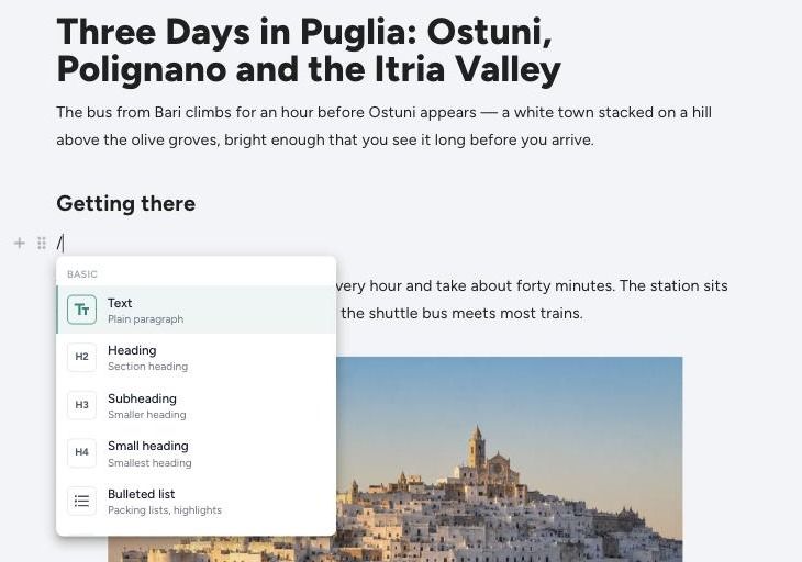 The slash menu open on a blank line in the TravelFeed editor, listing Text, Heading, Subheading, Small heading and Bulleted list