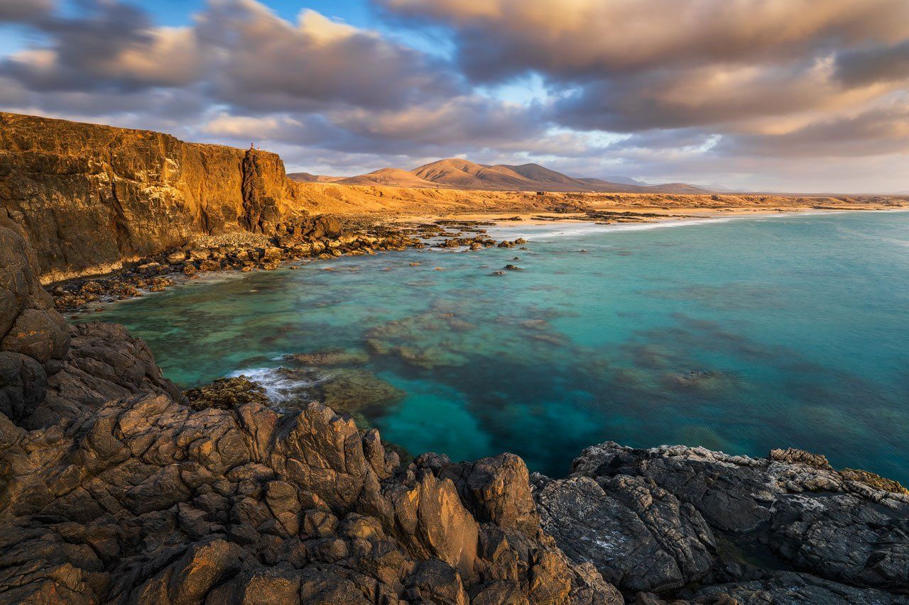 View across blue water to a golden beach near El Cotillo