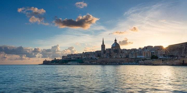The sun peeks over the roofs of Valletta