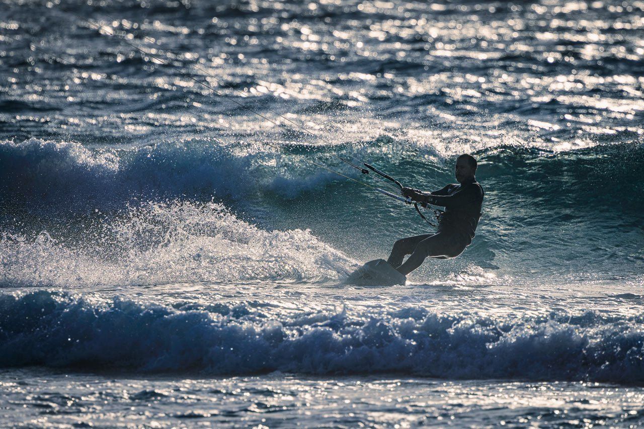 A backlit Kite Surfer braving the waves