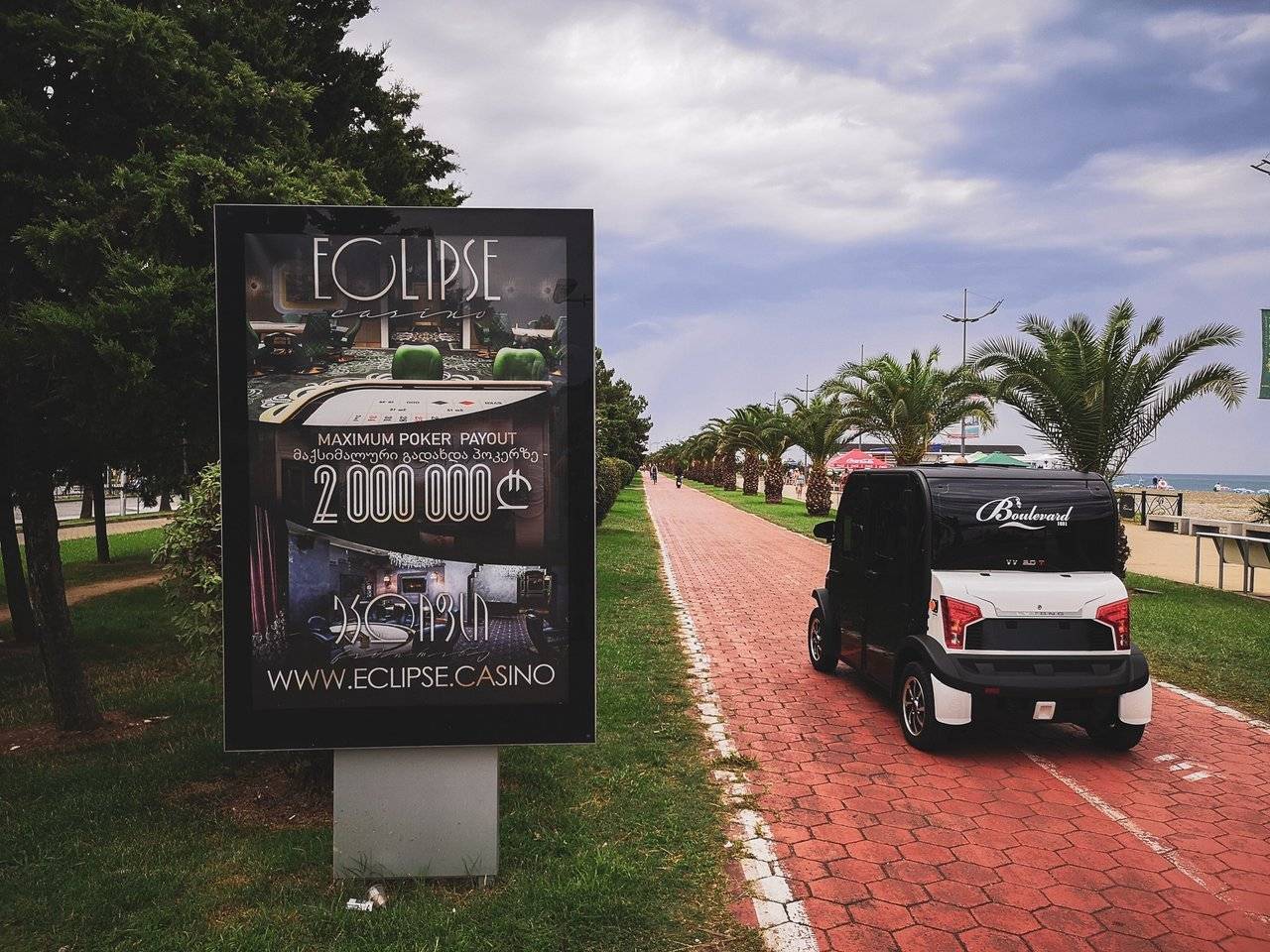 Golf car passing Casino Advertisement in Batumi CIty Promenade, Georgia