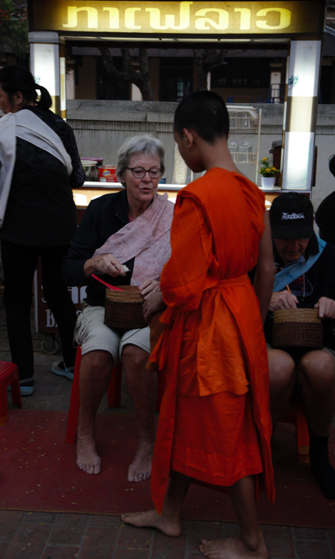 Some tourist join to give food for the monk