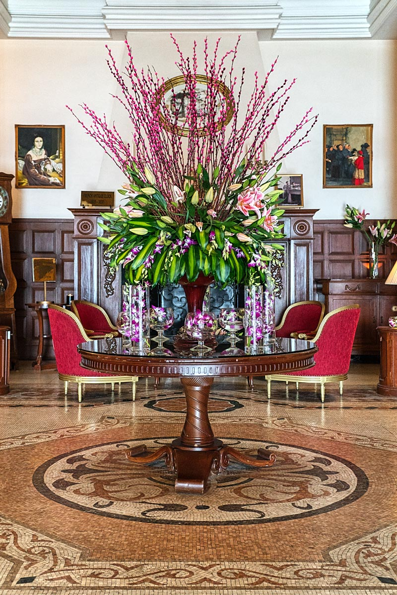 Grand lobby with a fireplace at the back and a splendid flower arrangement in the front.