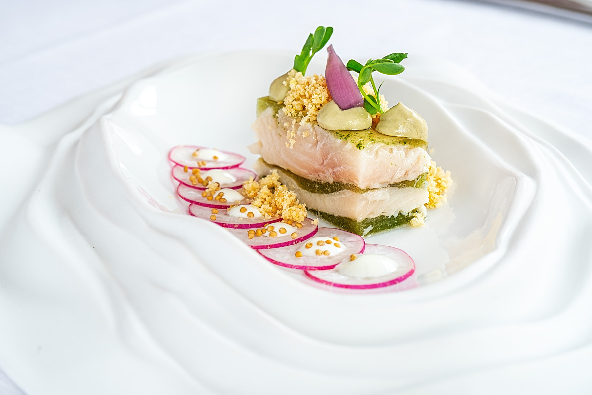 Trout terrine with celery, guacamole, pickled red onion, and almond crumble, next to the fresh radish slices topped with yogurt and mustard seeds.