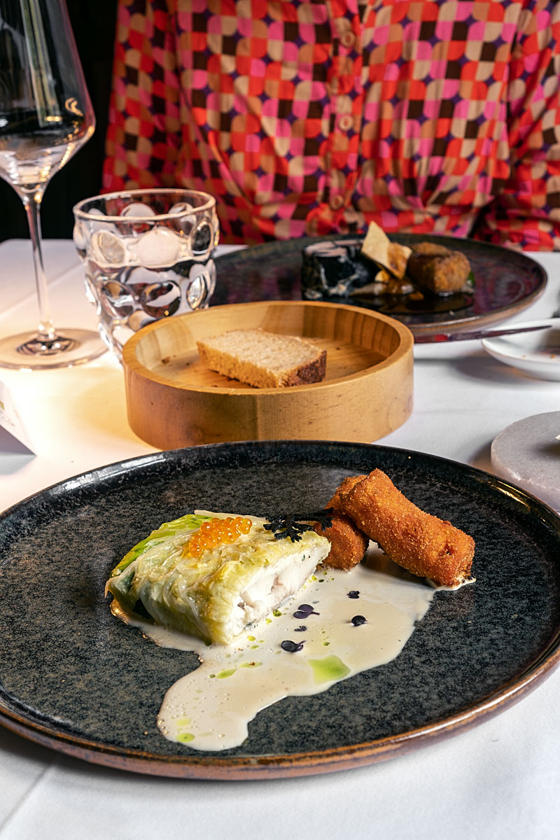 Steamed seabass in savoy cabbage with fritters and sauce