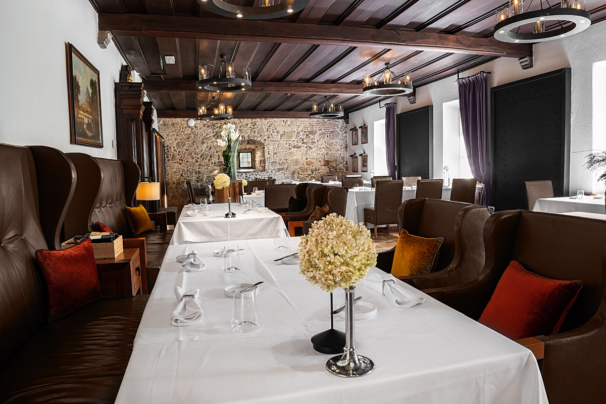 Stone walls, dark timber and crisp white tablecloths give the castle restaurant its quietly formal atmosphere.