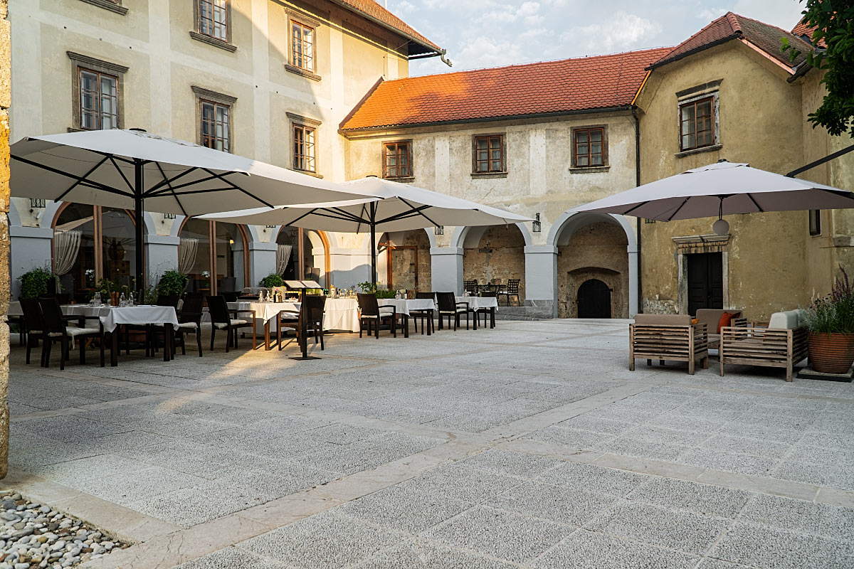 In fine weather, tables spread beneath parasols inside the peaceful castle courtyard.