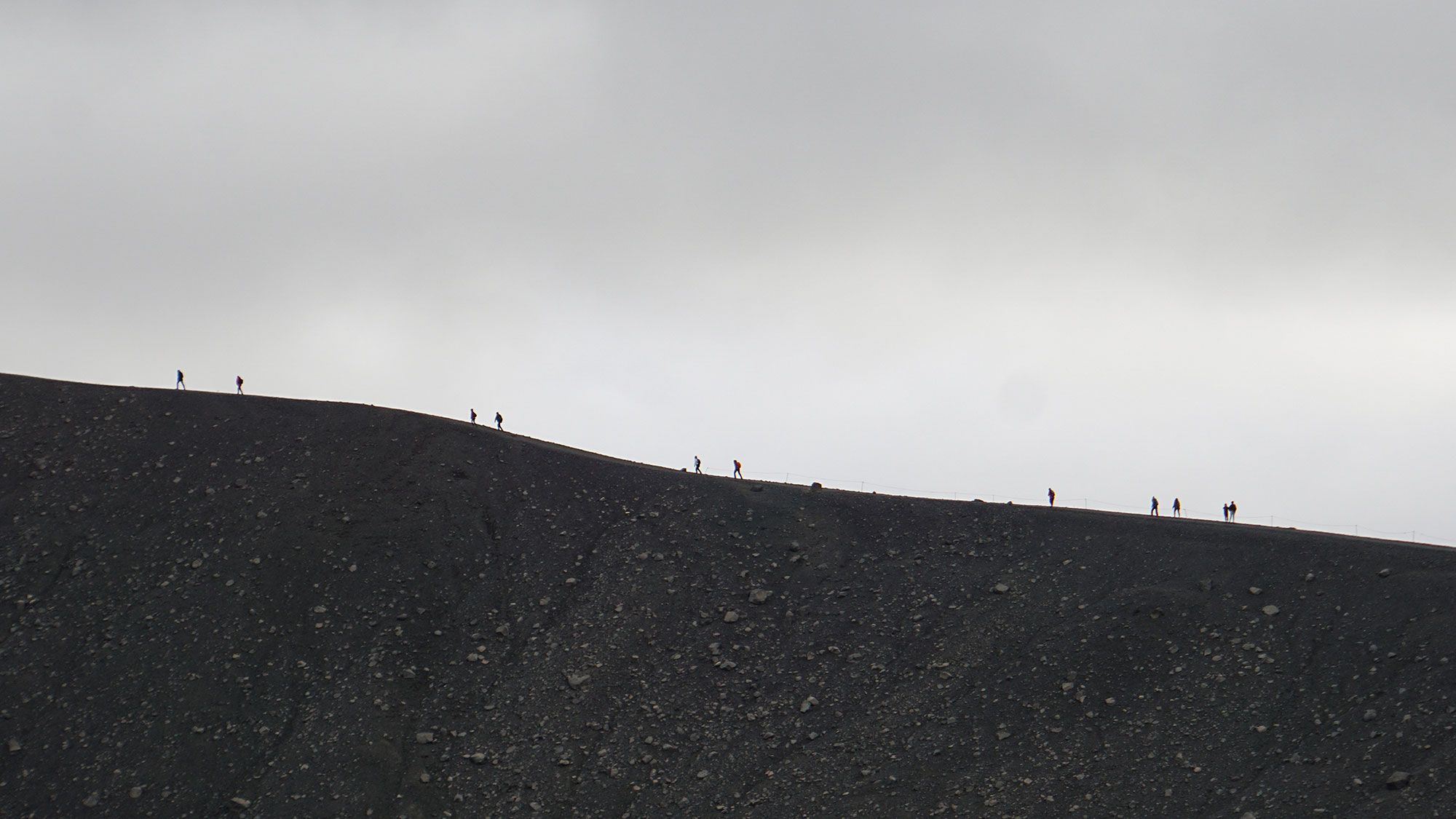 Tiny human figures on the rim - how small we are next to the power of nature.