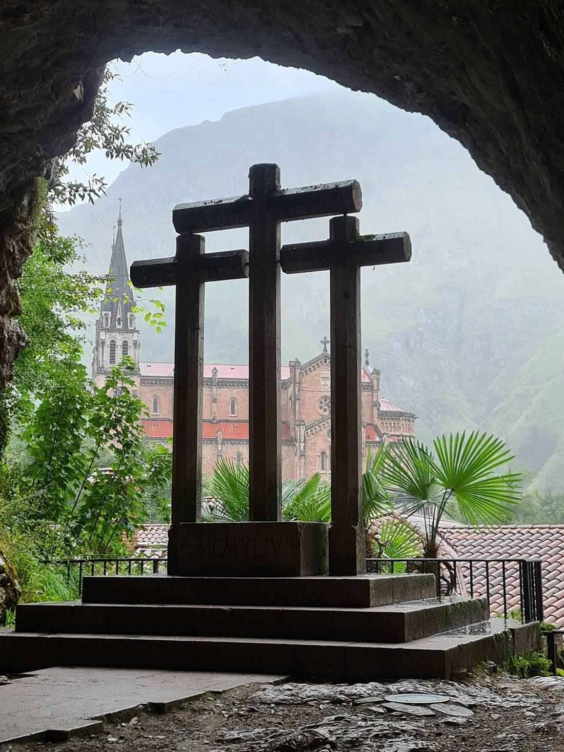 Three stone crosses, inside the Cave Sanctuary of Covadonga. At the bottom of the image we see the Basilica of Santa María la Real de Covadonga, from the side.