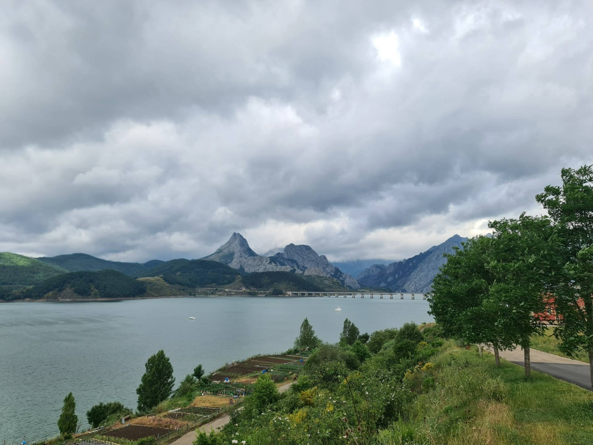 Small orchards on the banks of the Riaño reservoir and the Riaño bridge and the Gilbo peak in the background.