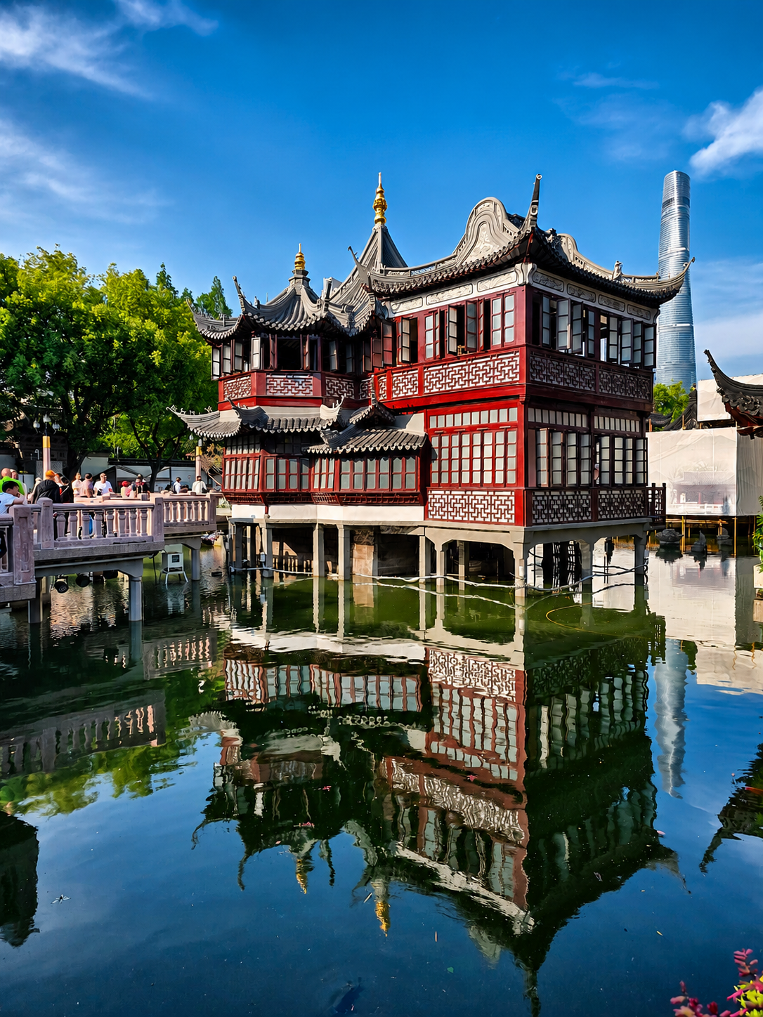 Traditional architecture reflected in the water, with Shanghai Tower rising behind it.