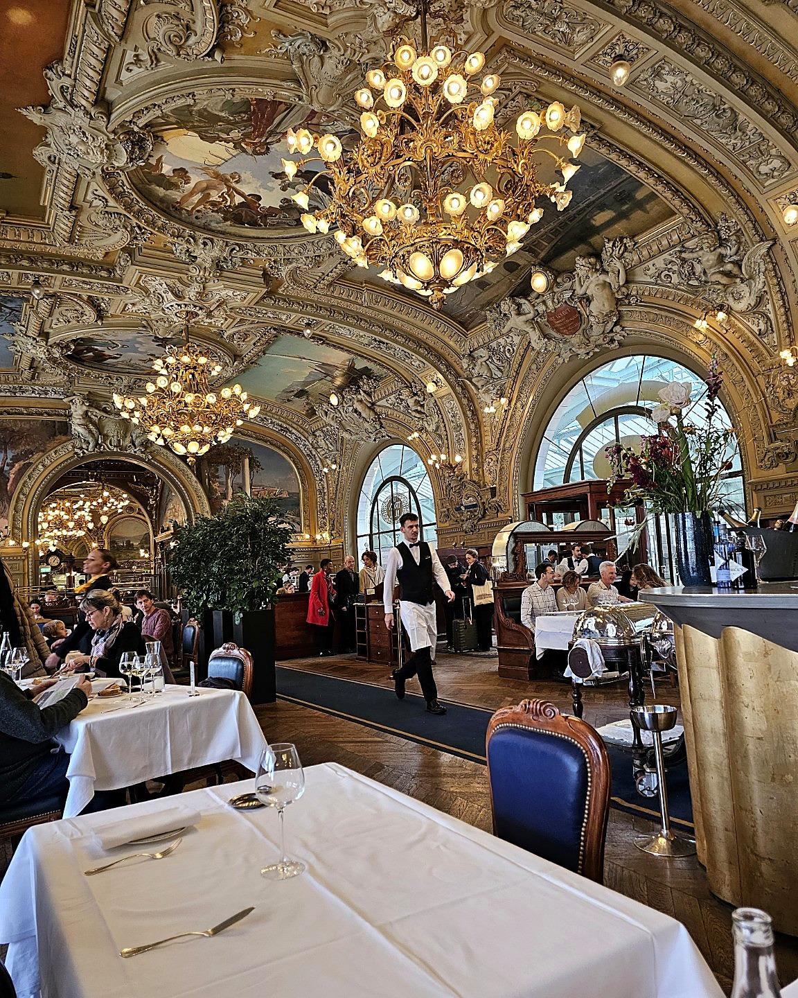 At Le Train Bleu, lunch unfolded beneath chandeliers, gilded stucco and painted ceilings designed to make moderation look entirely inappropriate.