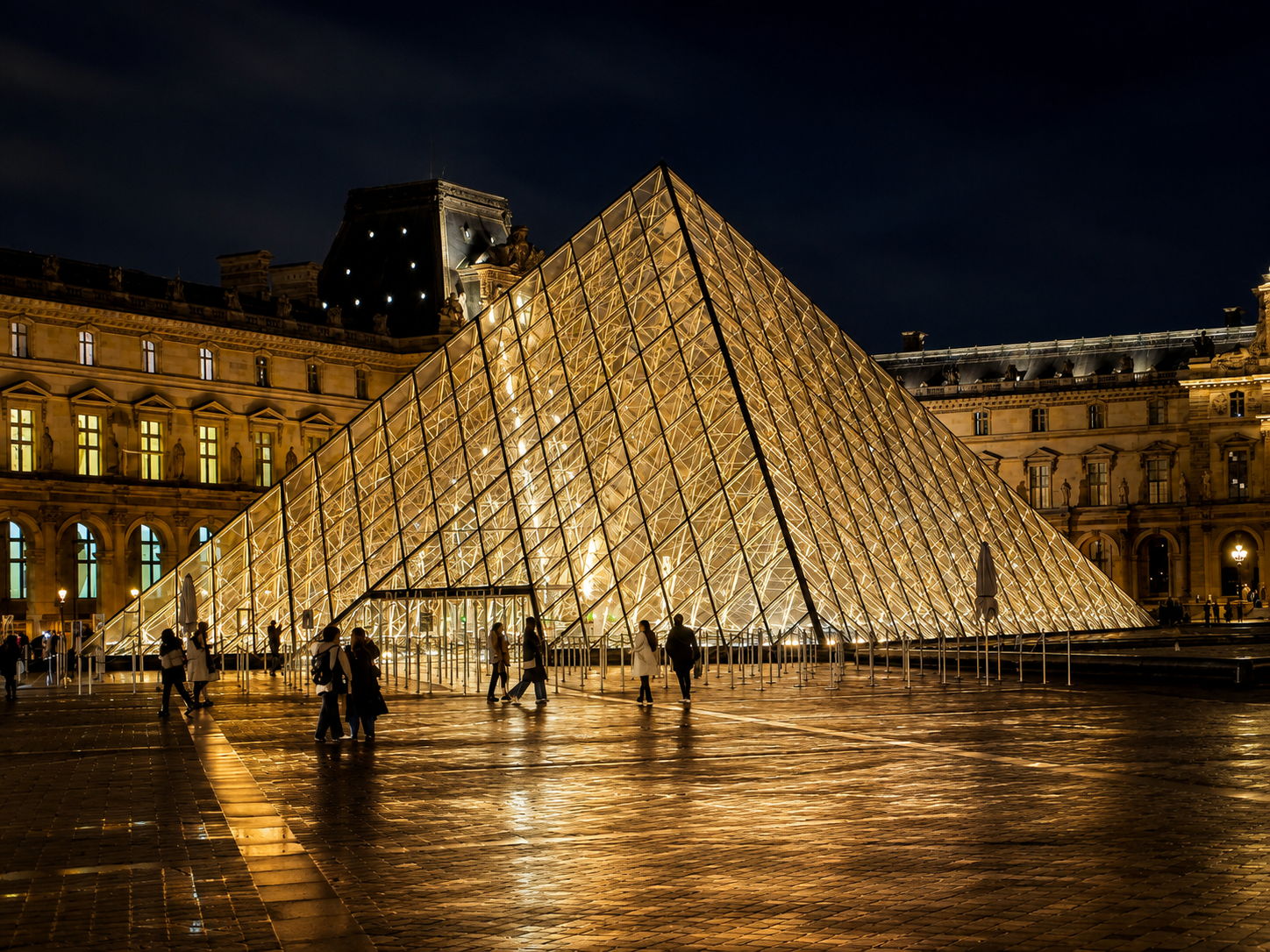 The Louvre Pyramid after dark, when the courtyard becomes less museum entrance than illuminated theatre.