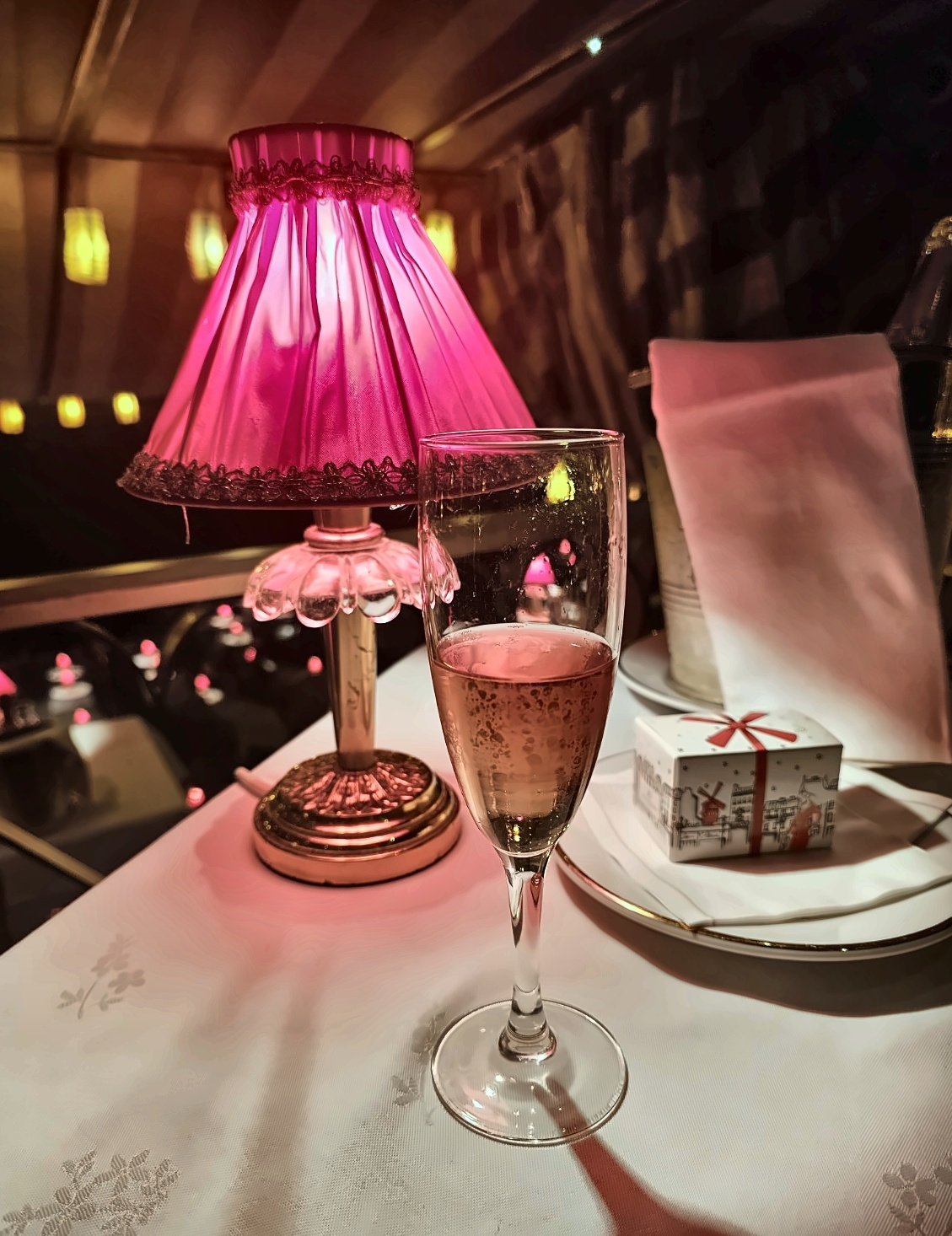 Champagne beneath the red table lamp — subtlety had clearly been refused entry along with restraint.