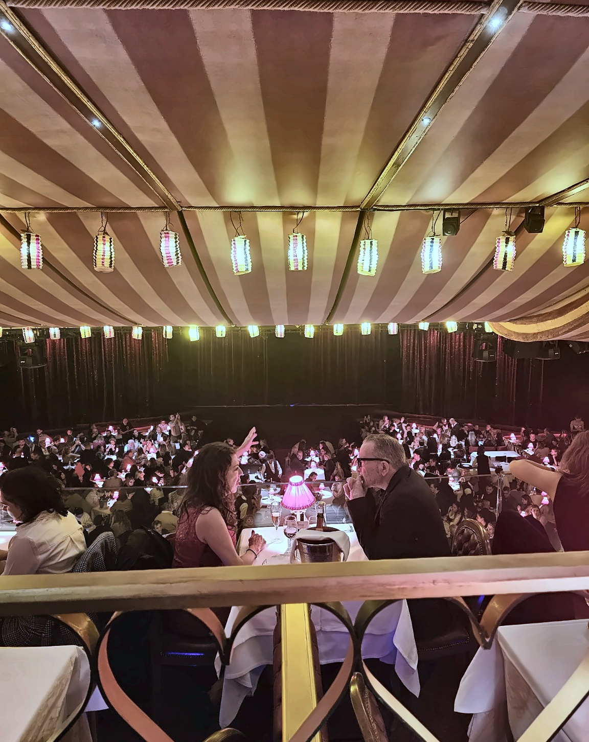 The Moulin Rouge auditorium before the curtain rose — hundreds of small red lamps turning dinner into part of the spectacle.
