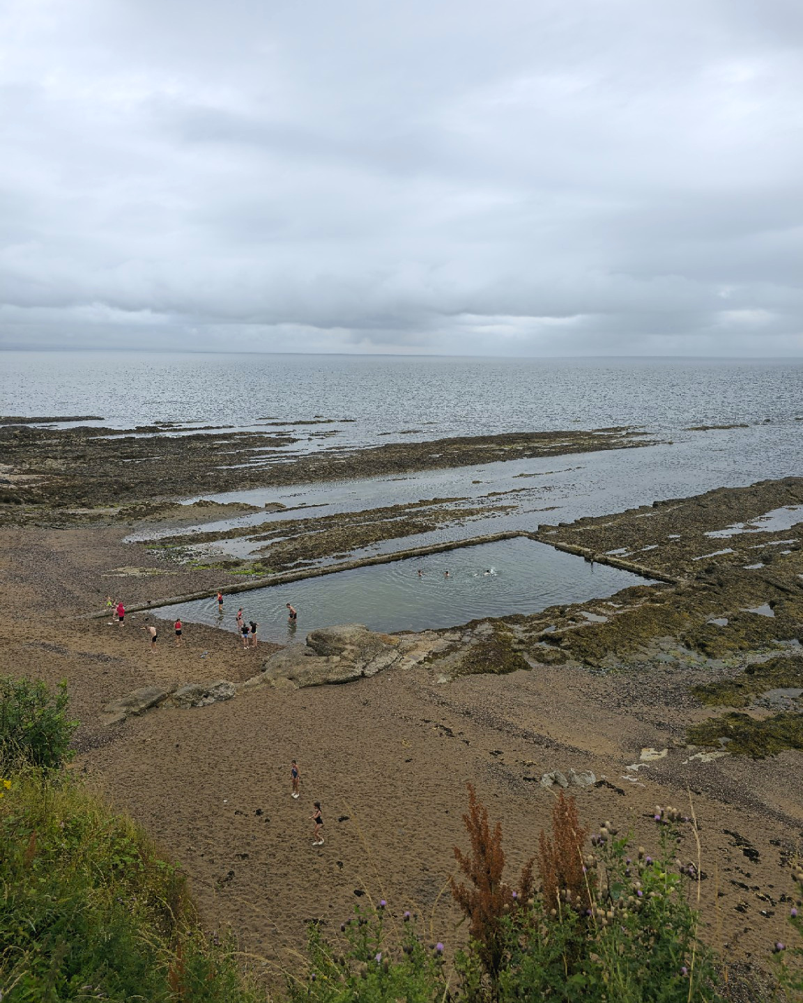 Below the castle, the North Sea withdraws across dark rock shelves, leaving the coastline as severe and theatrical as the ruins above.
