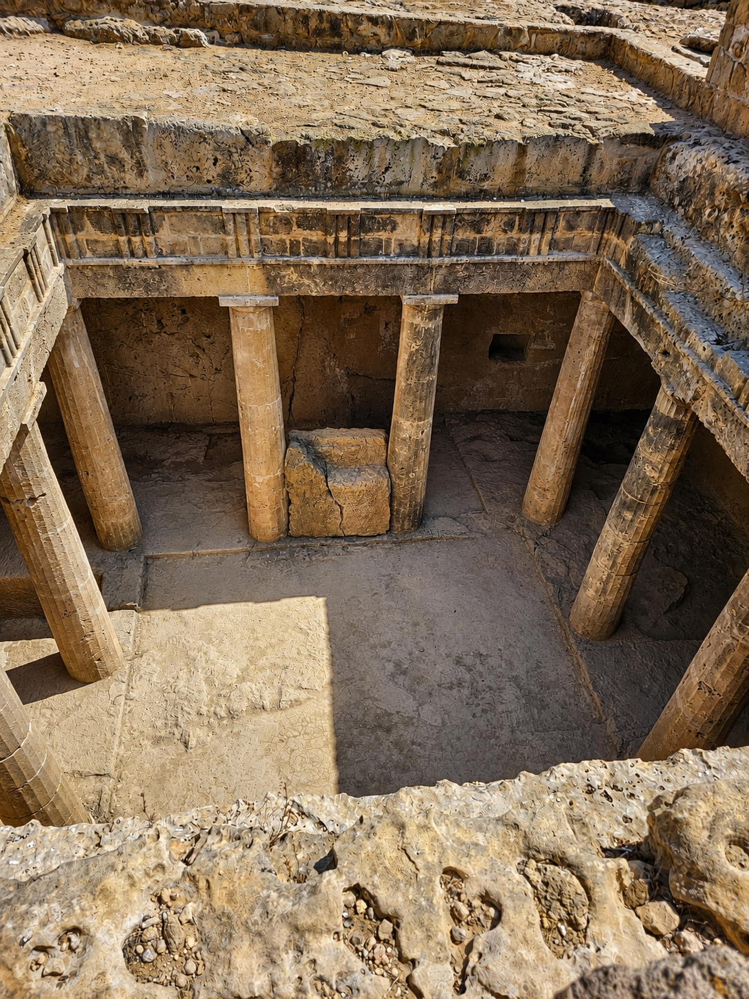 The sunken courtyard of the Tombs of the Kings, where rock-cut chambers borrowed the architecture of the living.