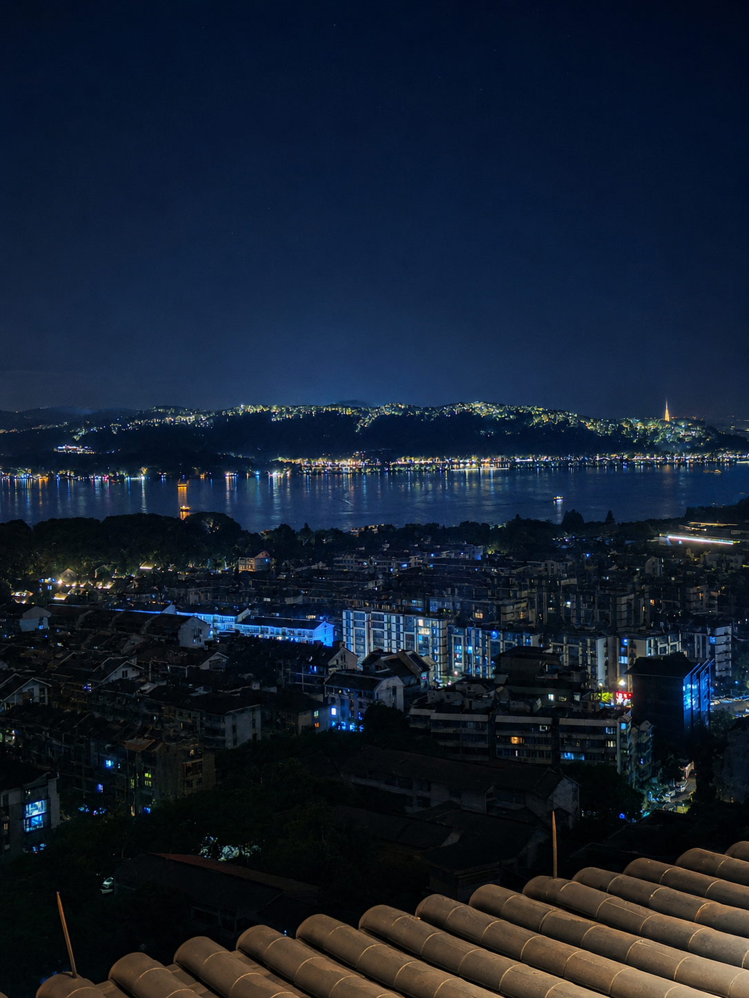 Night over West Lake, with Hangzhou shimmering in the distance.