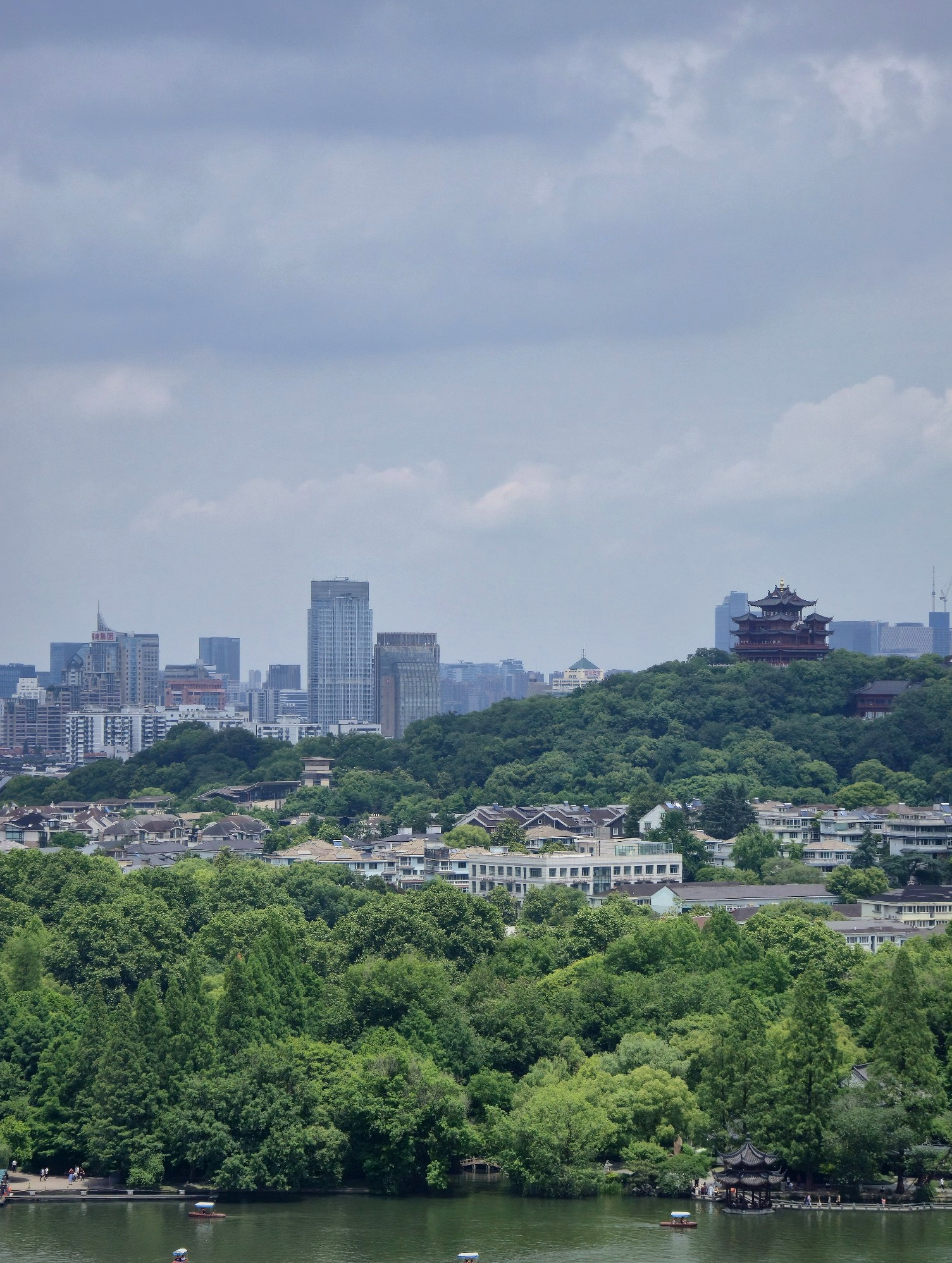 Hangzhou beyond the greenery, with Chenghuang Pavilion rising on Wushan Hill in the distance.