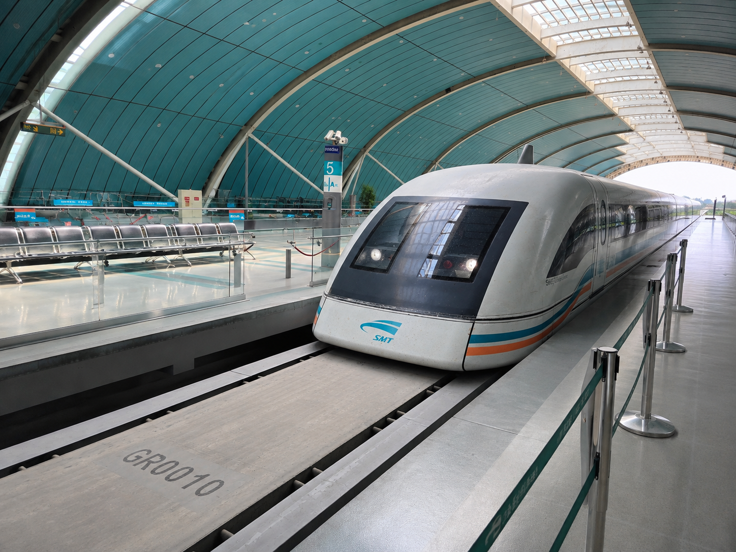 Shanghai Maglev train at a station platform beneath a curved turquoise-and-white roof.