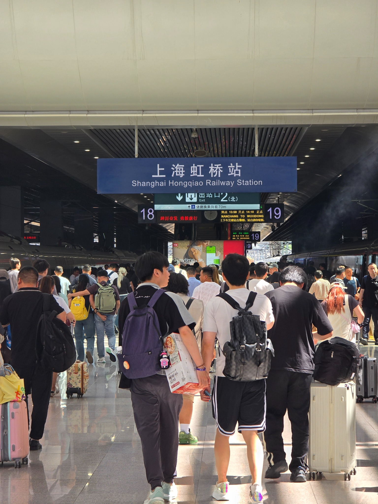 Travelers walk beneath the Shanghai Hongqiao Railway Station sign toward platforms 18 and 19.