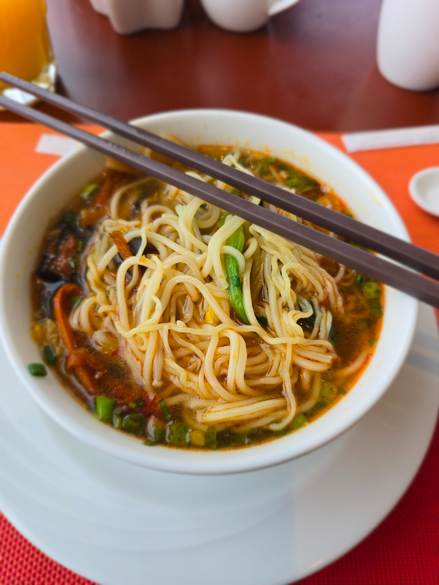 Bowl of noodle soup with chopsticks resting across it on a restaurant table.