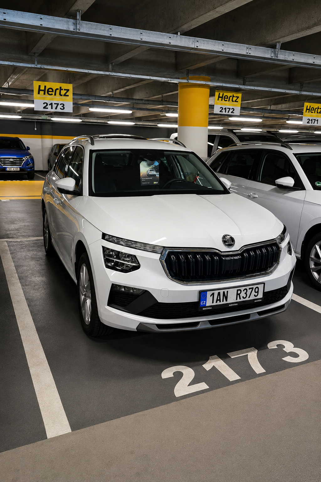 White Škoda car parked in a Hertz rental space numbered 2173 in a covered garage.