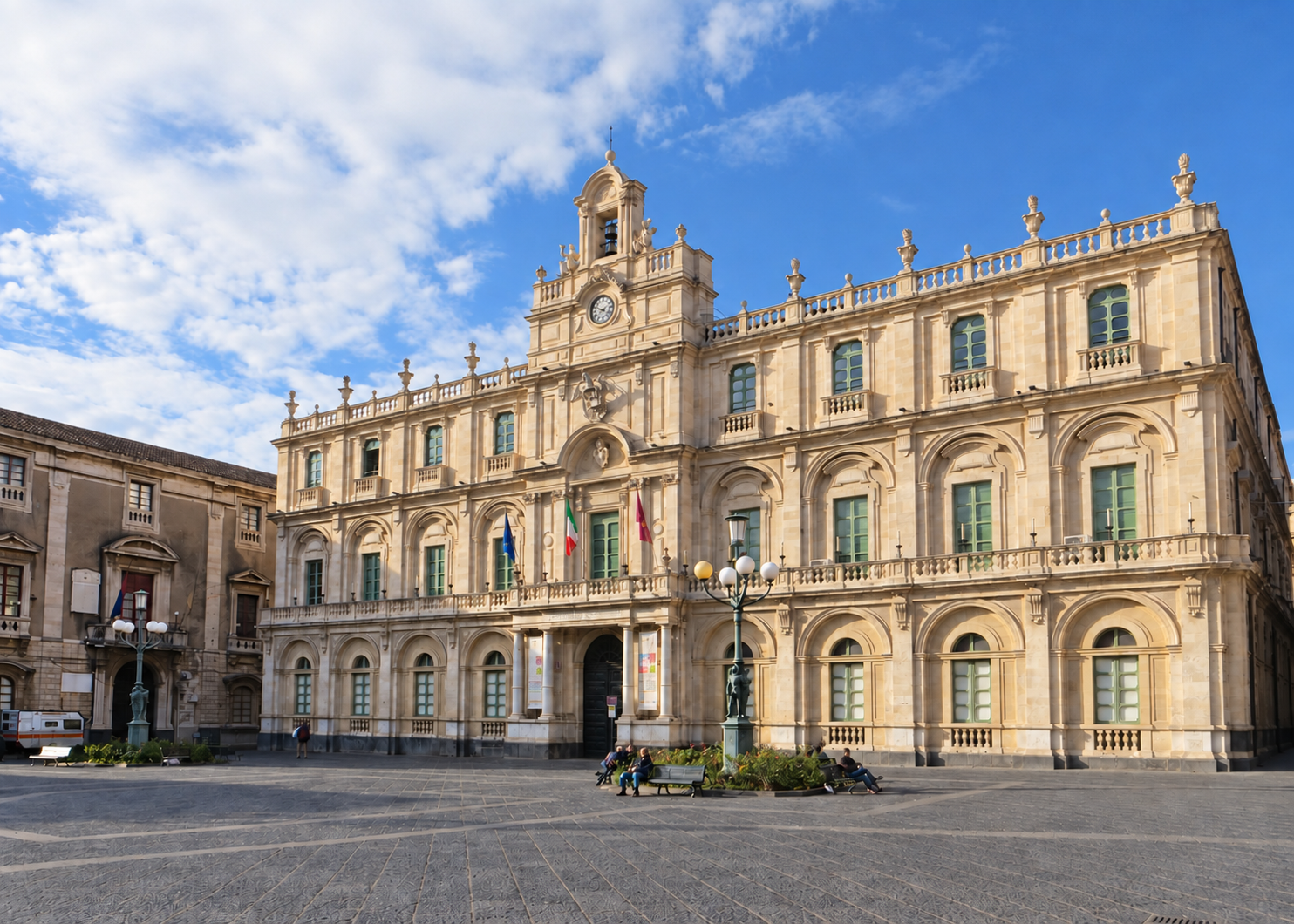 Palazzo Università overlooks a broad paved square in Catania, beneath a blue sky.