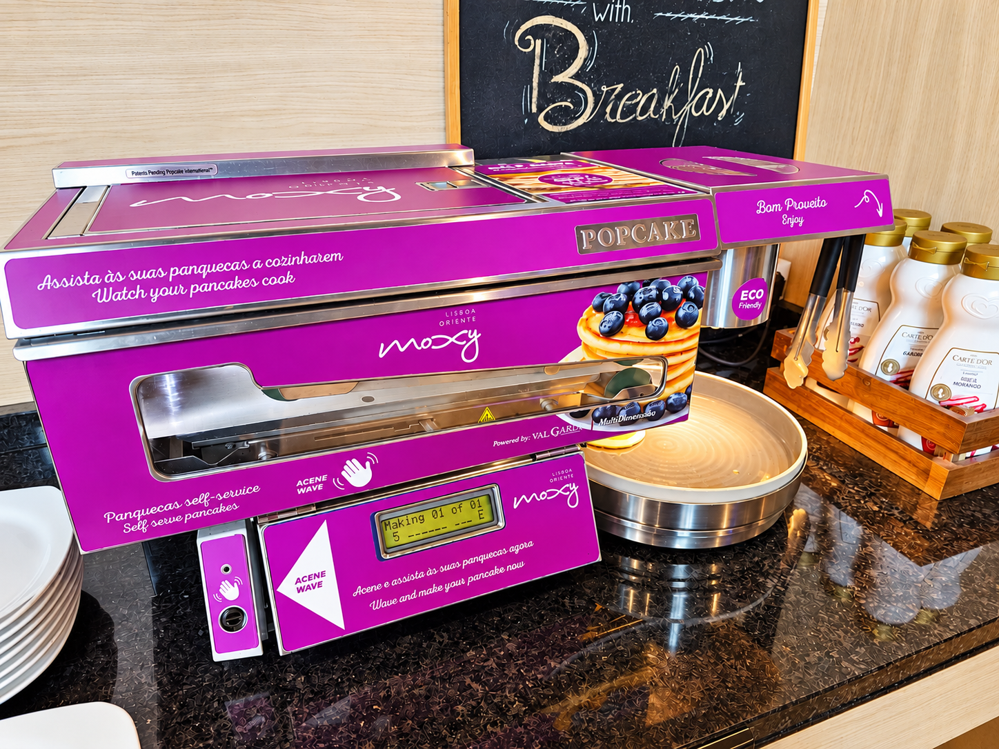 Pancake-making machine beside a plate of pancakes and blueberries on a breakfast counter at Moxy.