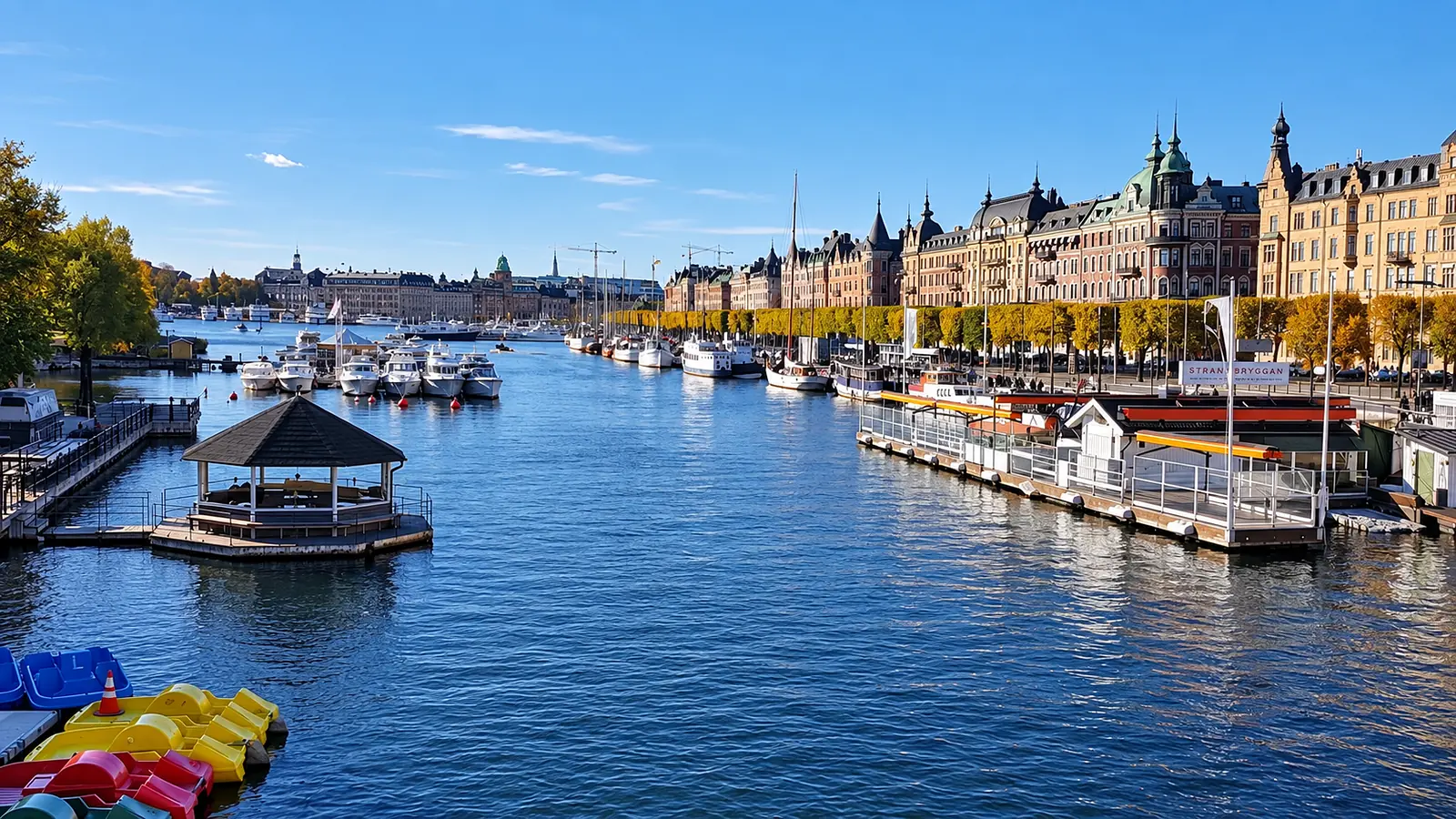 Stockholm waterfront lined with colorful historic buildings, docks, and boats under a clear blue sky.