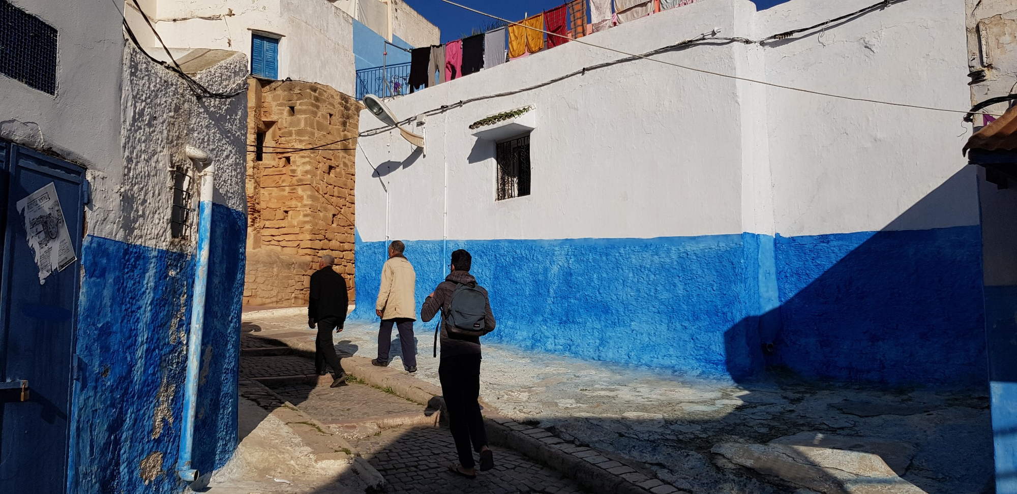 Three people walk through blue-and-white lanes in Rabat’s kasbah.