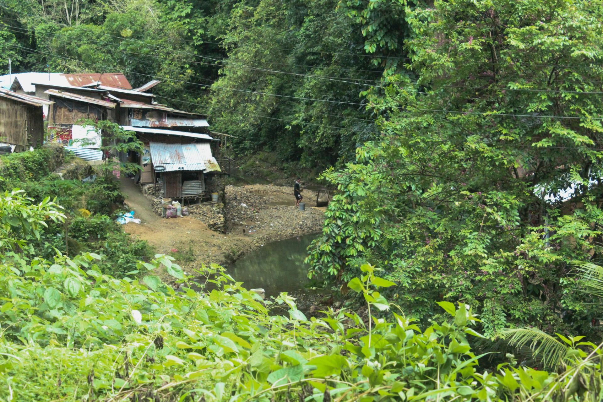 Man fetching water, his house by the clear river.