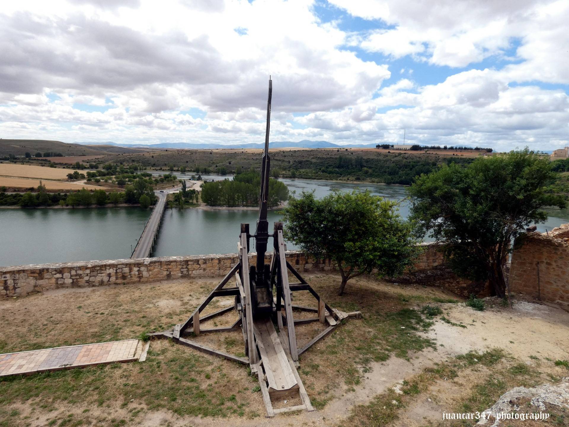 An old catapult watches over the bridge that rises over the waters of the Linares reservoir