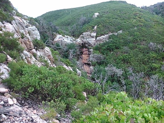Looking north with back to the sea, one can observe the waterfall trickling down to eventually meet the shoreline.