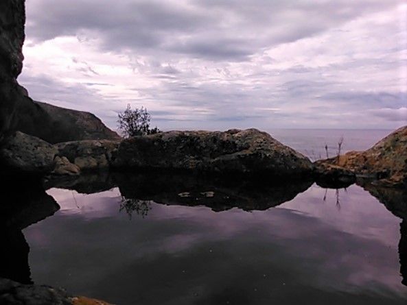 Monochrome image of the sky reflected in a rock pool on the cliffside overlooking the Indian ocean