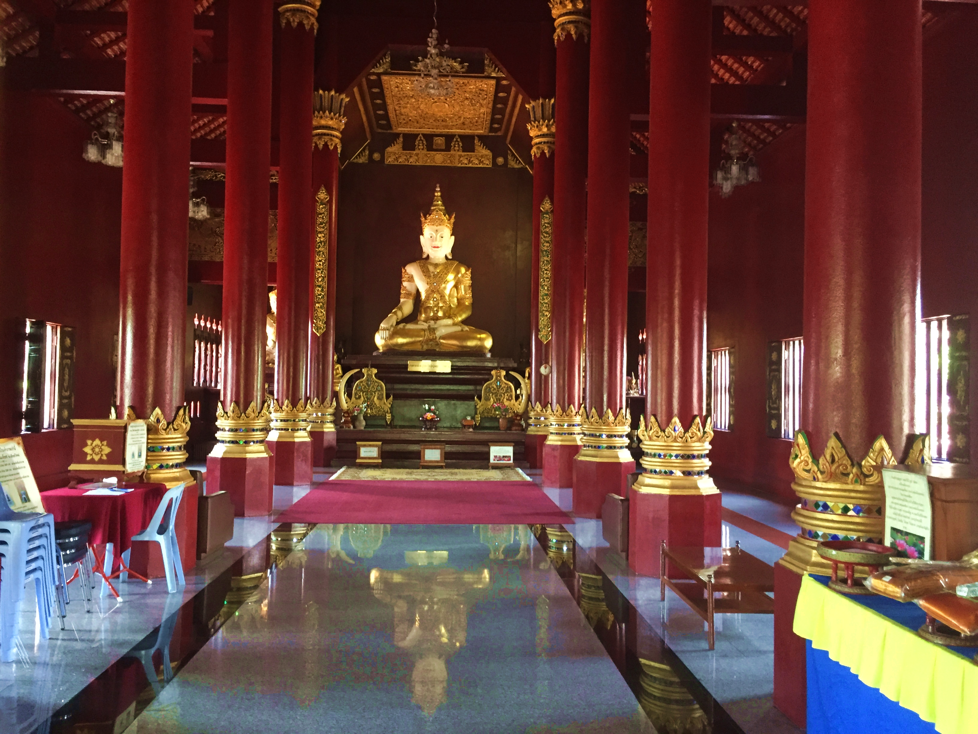 The special interior of Wat Monthian with its red and golden columns and a buddha statue