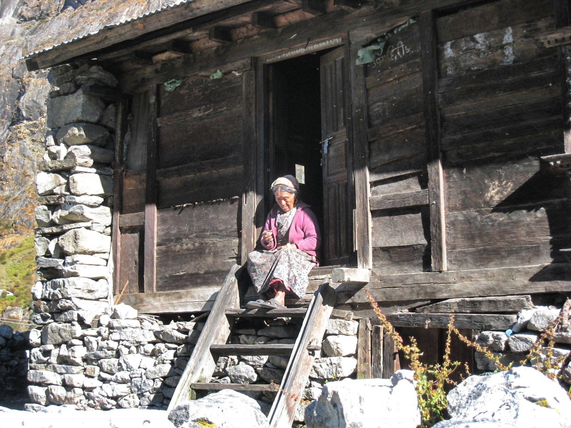 Elderly woman in front of her house