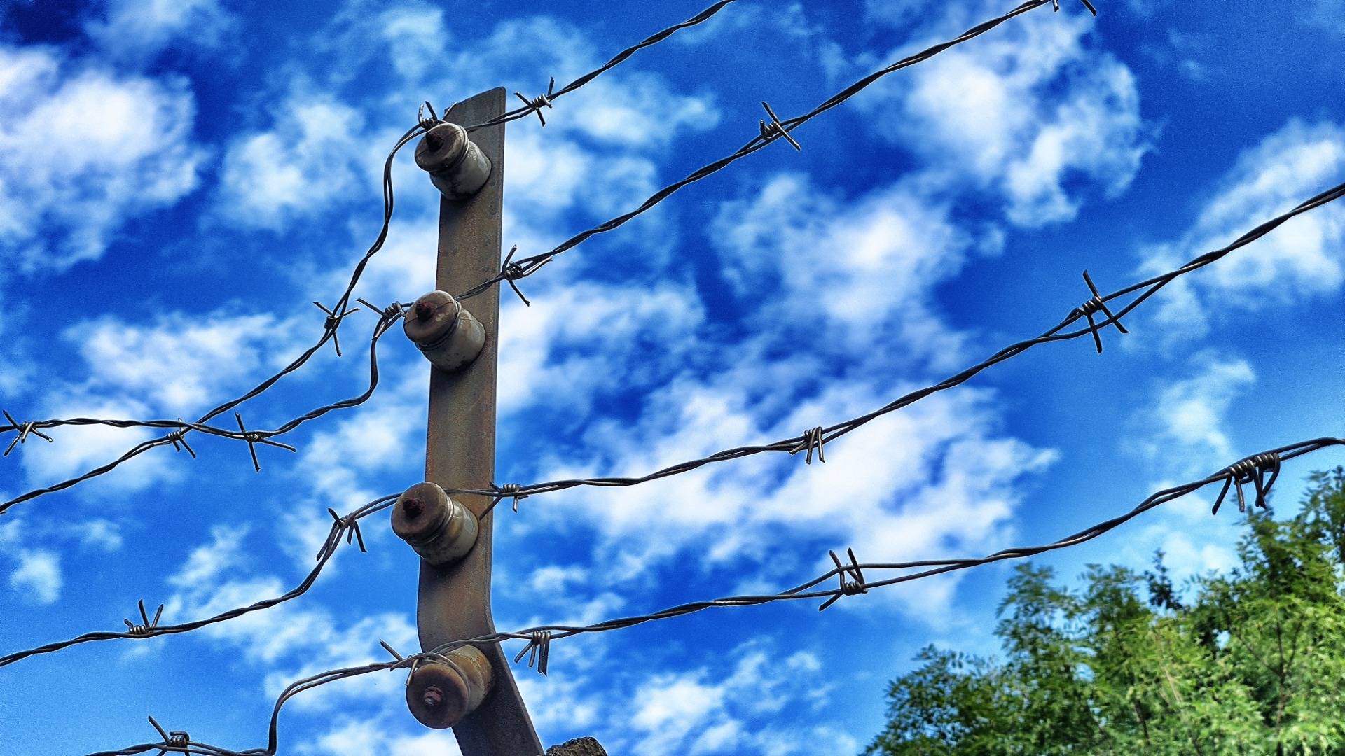 Barbed wire under a cloudy blue sky