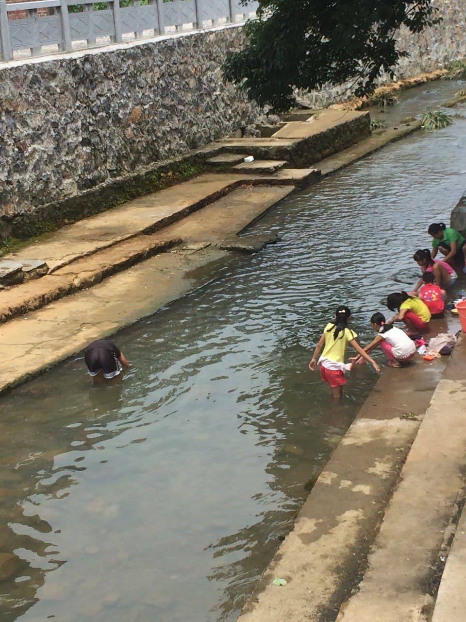 People were washing their clothes in the small river.