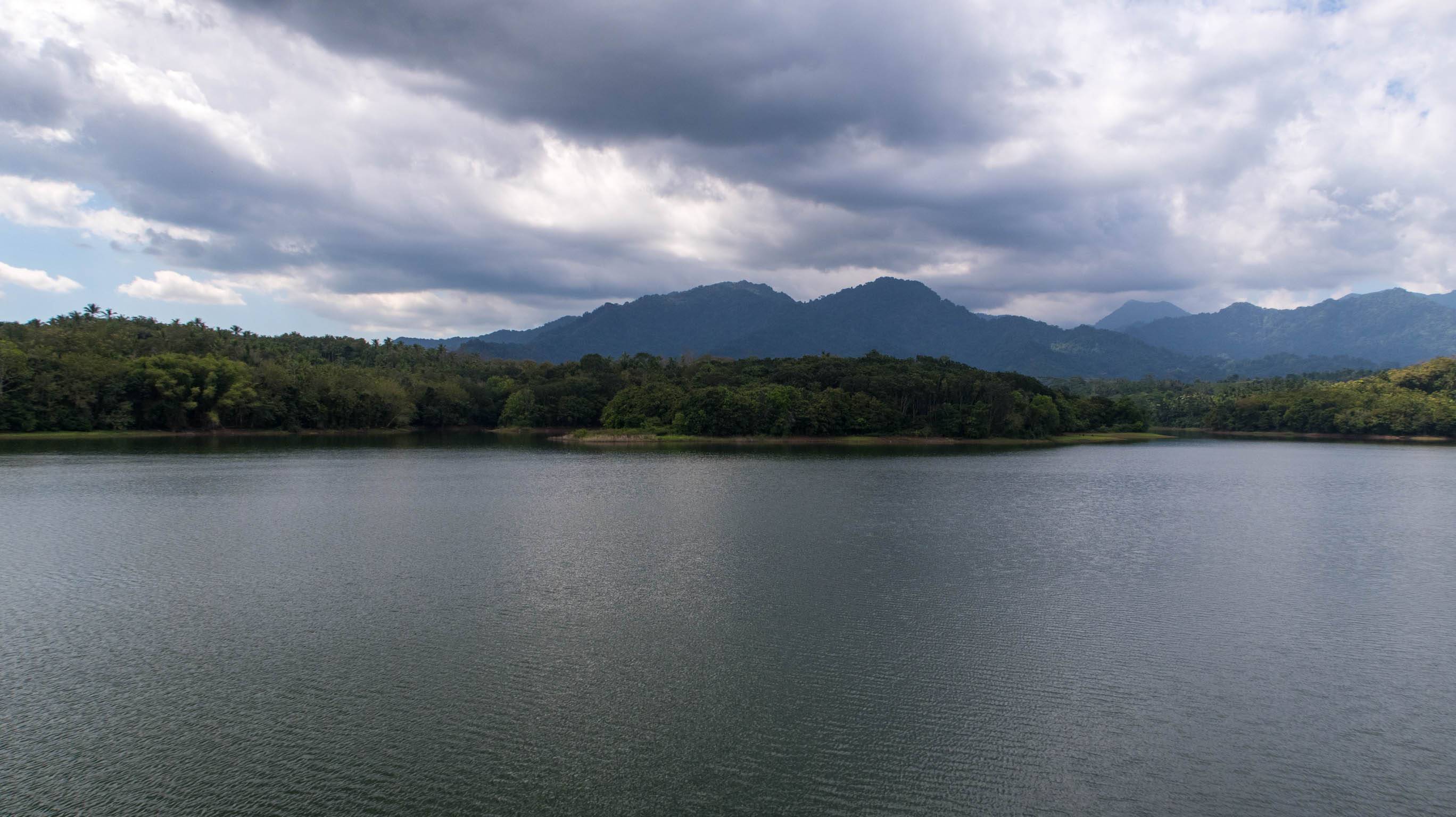 The view of Palasari Dam with forest and hills in the background.