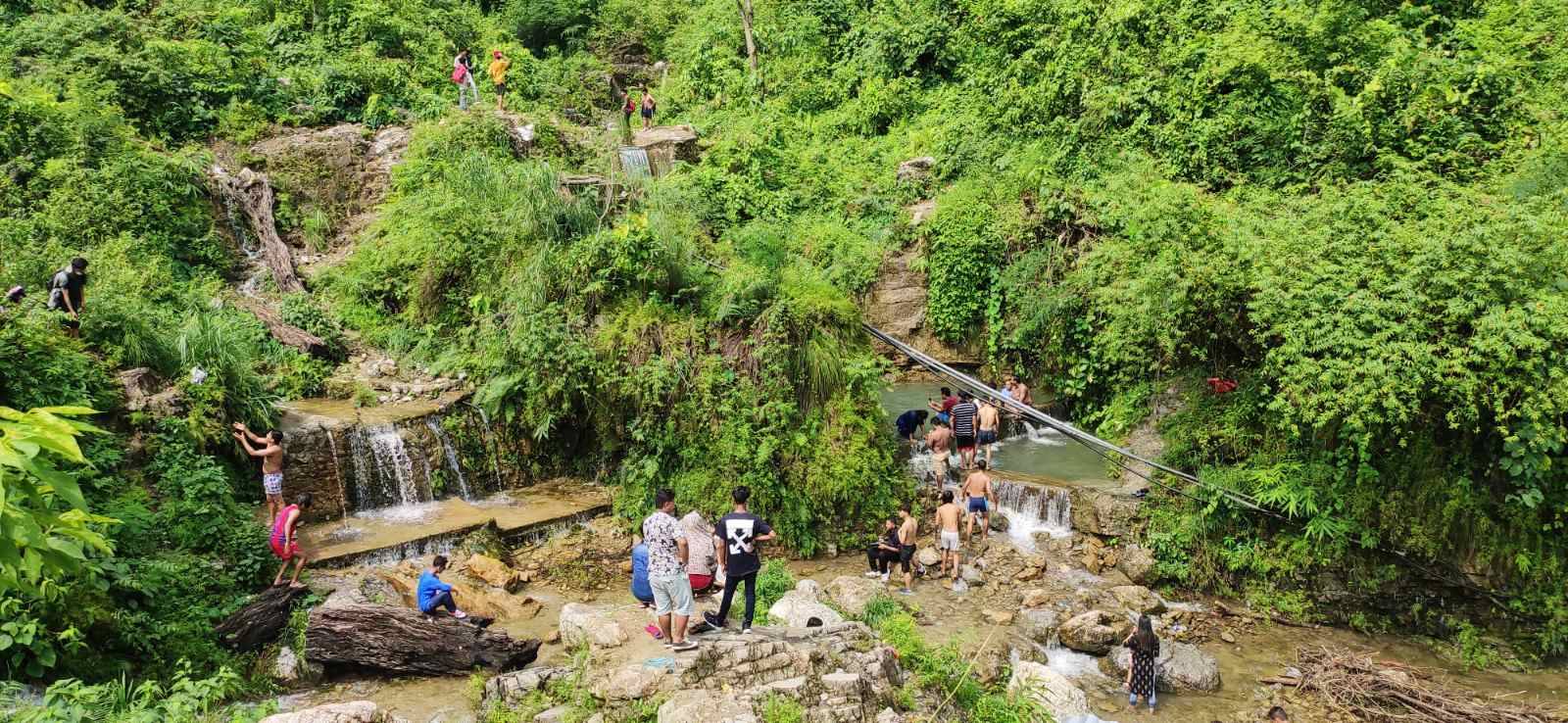 People enjoying the waterfall to escape from scorching heat.